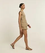 Short pollera de poliéster color beige, de corte sastrero, con cintura alta, pliegues delanteros y cintura lisa.