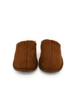 Pantuflas de gamuza color marrón con interior de corderito sintético blanco y costura central reforzada.