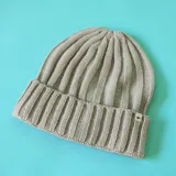 Gorro tipo beanie de tejido acanalado en color marrón, con borde doblado y etiqueta pequeña con el logo N+.
