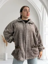 Campera marrón de tela tipo teddy con cierre frontal, cuello alto y bolsillos laterales.