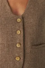 Chaleco marrón de lana con escote en V y cierre con botones.