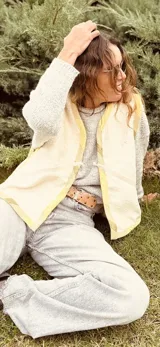 Chaleco color crema con ribete amarillo, de corte recto y sin mangas.