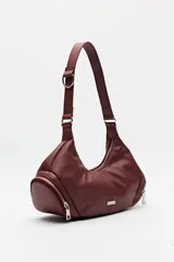 Cartera de hombro color bordó, de símil cuero, con diseño curvo y detalles de cierres metálicos en los extremos.
