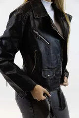 Chaqueta de cuero sintético marrón con diseño estilo biker, solapas con botones a presión, bolsillos con cierre y un pequeño bolsillo con solapa en la parte inferior frontal.