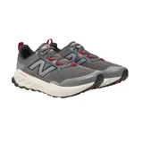 Championes de trail running New Balance MTGAROG2, color gris con detalles en negro y rojo.