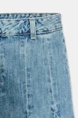 Falda de jean de tiro medio con efecto lavado, diseño con godets y costuras marcadas. Presenta un bajo asimétrico con acabado desflecado, cierre frontal con cremallera y botón metálico.