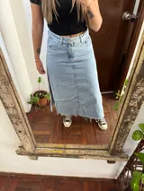 Pollera midi de denim celeste claro, de tiro medio, con bolsillos laterales y traseros, costura frontal central y dobladillo deshilachado.
