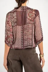 Blusa de manga corta abullonada, con escote en V y detalle de lentejuelas bordadas a lo largo de la abertura. Estampado estilo paisley en tonos borgoña y marrón.