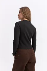 Polera de manga larga con cuello alto, confeccionada en tejido de algodón con textura acanalada y calce ajustado al cuerpo.