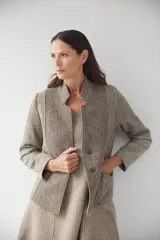 Chaqueta corta color marrón con cuello solapa y diseño con patchwork de telas. Manga larga con detalle de coderas aplicadas. Cierre frontal mediante botones y bolsillos ojal. Con forro.