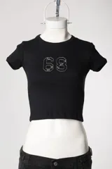 Baby tee de calce al cuerpo y manga corta, con cuello redondo y diseño con tachas frontales.