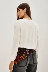 Remera de manga larga en color blanco, confeccionada en una mezcla de lino y viscosa. Presenta un escote en V con detalle de solapa y puños rectos.