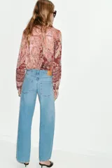 Jeans de tiro bajo color azul claro, con cinco bolsillos y pernera ancha. Cierre frontal con cremallera y botón.