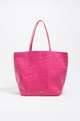 Bolso shopper de tamaño grande de cuero color fucsia, con textura efecto cocodrilo. Presenta doble asa de hombro y logo metálico de la marca en la parte inferior frontal.