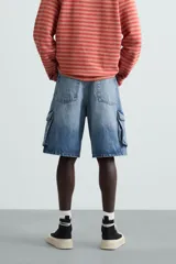 Bermuda de denim de algodón, color celeste lavado, de corte relajado (relaxed fit). Presenta cinco bolsillos, incluyendo bolsillos cargo plastrón con solapa en las perneras.