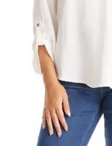 Blusa de color blanco con escote en V y cuello mao. Presenta mangas largas con presilla y botón para regular el largo, y un corte holgado con ruedo redondeado.