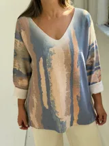 Sweater de tejido de punto con diseño abstracto en tonos azul, beige y rosado, de corte holgado y mangas largas con puños vueltos.