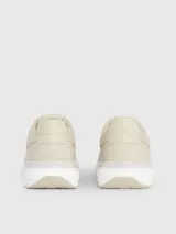 Zapatillas deportivas de mujer Calvin Klein, color beige claro, con cordones y suela gruesa blanca. Presentan una combinación de materiales que incluye piel natural y ecológica, con paneles de malla y detalles de monograma sutil en el lateral.