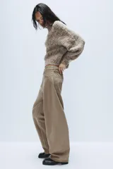 Jeans de tiro medio con diseño baggy barrel, confeccionados en denim color beige con efecto lavado. Presentan cinco bolsillos, costuras laterales torcidas y cierre frontal con cremallera y botón metálico.