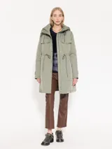 Parka verde militar de corte recto y holgado con cintura ajustable mediante cordón. Cuenta con capucha, bolsillos frontales con solapa y broches.