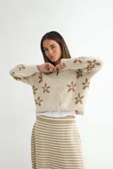 Cardigan de punto con diseño de flores estampadas, cuello redondo y cierre frontal con botones. Presenta un corte holgado y mangas largas.