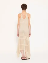 Vestido largo color beige, tejido en hilo fino con sutil brillo metálico. Diseño ajustado al cuerpo y con transparencia.