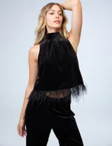 Conjunto de dos piezas compuesto por una musculosa de cuello alto con detalle de plumas en el ruedo y un pantalón de corte recto, ambos confeccionados en terciopelo negro.
