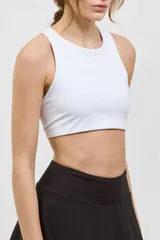 Top deportivo corto de sujeción media, con escote redondo clásico y espalda abierta. Presenta un diseño al cuerpo con elástico interno en la cintura.