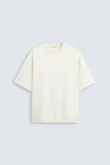 Sudadera de corte relaxed boxy fit, color blanco hueso, confeccionada en tejido interlock de algodón elástico. Presenta cuello redondo y manga corta con bajo acabado en rib.