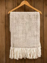 Pashmina de lana merino, tejida a mano con diseño texturizado en tono beige y detalles de flecos largos en los extremos.