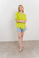 Camisa de lino color verde lima, de calce relajado, con cuello mao, botones al frente y bolsillo en el pecho. Las mangas son cortas y pueden usarse arremangadas.