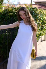 Vestido midi blanco sin mangas, de corte recto y holgado, con detalle de costura diagonal en relieve.