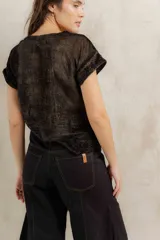 Remera de manga corta confeccionada en terciopelo con acabado brillante, de corte holgado y cuello redondo.