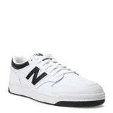 Championes New Balance modelo 480, de diseño inspirado en el básquetbol de los años 80. Presentan una capellada de cuero blanco con detalles en negro, incluyendo el logo lateral, el talón y la suela. Cuentan con cierre de cordones y perforaciones en la puntera para mayor ventilación.