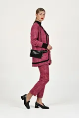 Conjunto de dos piezas compuesto por un saco tipo blazer de corte recto con cierre frontal de botones y ribetes negros en contraste, y un pantalón de vestir de corte recto a juego. Ambas prendas presentan un diseño de tejido texturizado en tonos rosa.