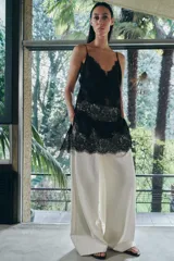 Top largo confeccionado en tejido de encaje con escote en pico y tirantes finos. Presenta una combinación de tejidos a tono con diseño sofisticado.