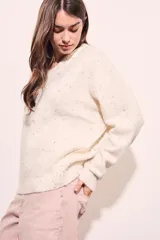 Sweater color crema con motas de colores, de corte oversize, cuello redondo y mangas largas.