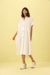 Vestido camisero blanco con botones y corte asimétrico.