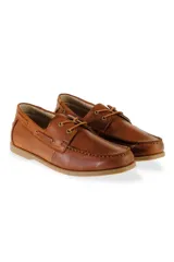 Mocasín de gamuza color camel, estilo náutico, con cordones finos en la parte superior y ojales metálicos.