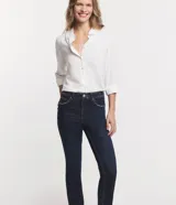 Pantalón de jean corte slim, color azul oscuro, con cierre de botón y cremallera, trabillas en la cintura y aberturas laterales en los bajos.