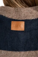 Sweater de tejido de punto color blanco roto o crema, con textura jaspeada. Presenta cuello polo y un escote con tres botones nacarados. El calce es holgado (oversize) y tiene mangas largas.