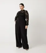 Pantalón de sastrería corte wide leg, color negro, con cintura alta, cierre de cremallera y gancho, y bolsillos laterales incorporados. Presenta elástico en la parte posterior de la cintura para mayor ajuste.