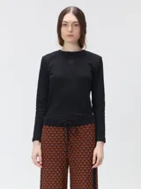 Pantalón de punto jacquard con diseño geométrico texturizado, de corte holgado y pierna ancha. Presenta tiro medio, cintura elástica con cordón ajustable y aberturas laterales en el ruedo.