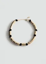 Collar de diseño metálico con piezas tubulares doradas texturizadas intercaladas con nudos de hilo negro, y cierre de cadena y mosquetón.