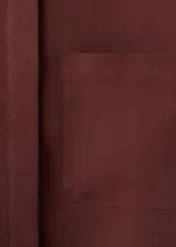 Camisa oversize color borravino, de manga larga con puños abotonados, cuello camisero, dos bolsillos de parche en el frente y cierre delantero con botones.