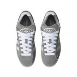 Championes Adidas modelo Campus 00s, color gris con las icónicas tres tiras laterales en blanco. Presentan una capellada de gamuza, cordones blancos, entresuela de color crema y suela de goma color caramelo.