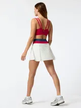 Skort deportivo blanco con pretina ancha tejida en colores fucsia y azul. Cuenta con short incorporado en el interior y diseño plisado central, inspirado en el estilo de tenis vintage.