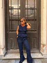 Musculosa de jean azul oscuro, sin mangas, con diseño fruncido tipo corset en el torso y terminación con volados en la cintura.