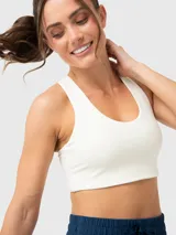 Top deportivo blanco con soporte medio, almohadillas removibles y detalles de encaje en tirantes y bajo busto. Espalda con tirante grueso central.