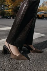 Zapato destalonado de gamuza color marrón con tacón en bloque de altura media y punta fina. Presenta una tira trasera con elástico para mayor ajuste.